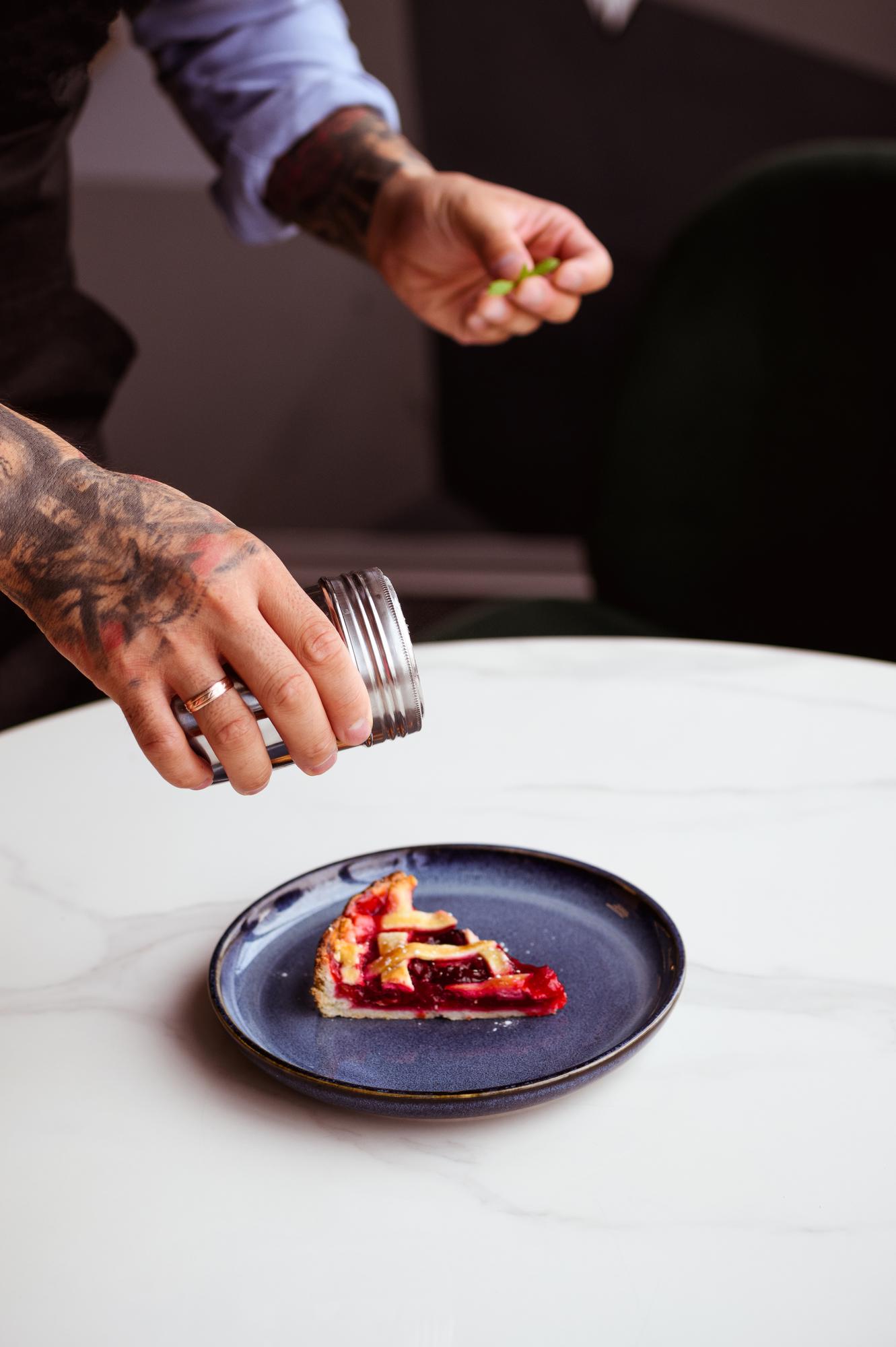 Chef demonstrating plated dish on wooden table